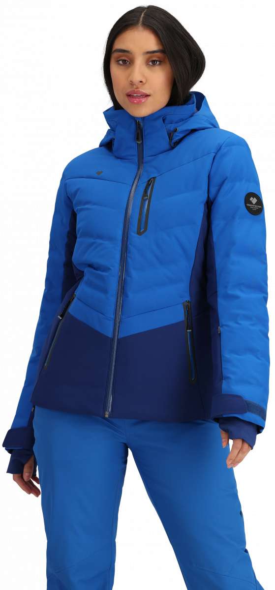 Obermeyer Women's Cosima Down Jacket - A royal blue down jacket with a high collar and zippered pockets, featuring a black zipper pull on the chest pocket.