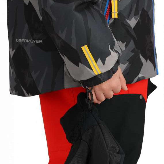 Obermeyer Youth Ashor Insulated Jacket 2024 - A black and grey camouflage patterned jacket with a blue zipper on the chest pocket.