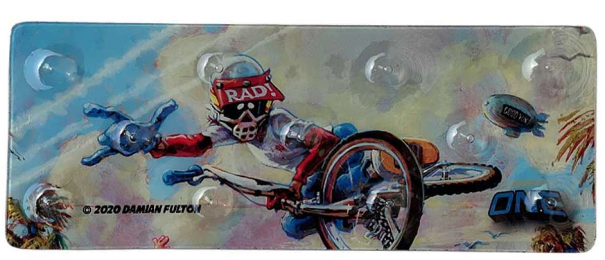 Oneball Radical Rick Stomp Pad - A blue cartoon character with a red shirt and helmet, riding a snowboard down a mountain.