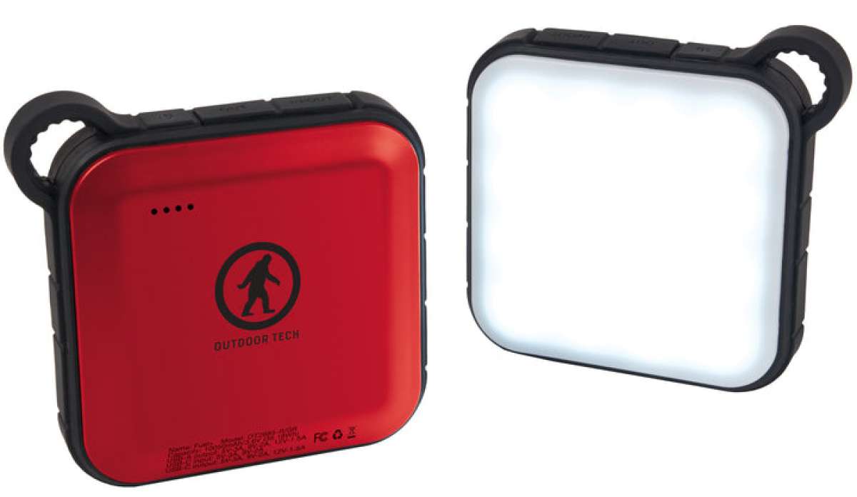 Outdoor Tech Fuel Lantern Power Bank - A red square power bank with a circular logo featuring a person skiing in the center, and three small black dots above it.