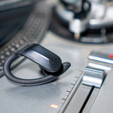 Outdoor Tech Mantas 2.0 Wireless Earbuds - Black earbuds with silver accents and a black charging case on a gray background.