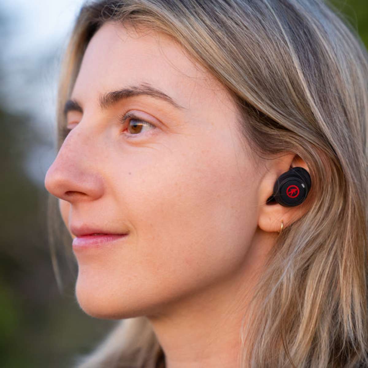 Outdoor Tech Pearls Wireless Earbuds - Black earbuds with red logo on each bud, worn in woman's ears.