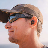 Outdoor Tech Pearls Wireless Earbuds - Black earbuds with red logo on right bud, worn by a man in profile view.