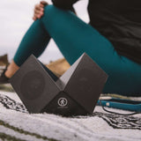 Outdoor Tech Twin Peaks Portable Speaker - A black portable speaker with a mesh grille and two speakers on either side of the top, angled slightly outward.