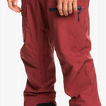 Quiksilver Utility Shell Pant 2023 - A pair of red snow pants with a zippered pocket on the thigh and a black zipper pull.