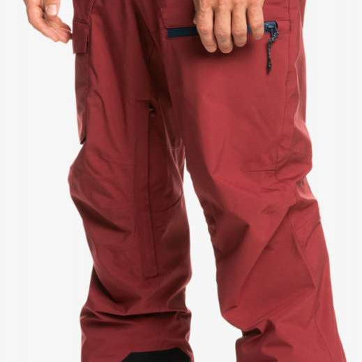 Quiksilver Utility Shell Pant 2023 - A pair of red snow pants with a zippered pocket on the thigh and a black zipper pull.