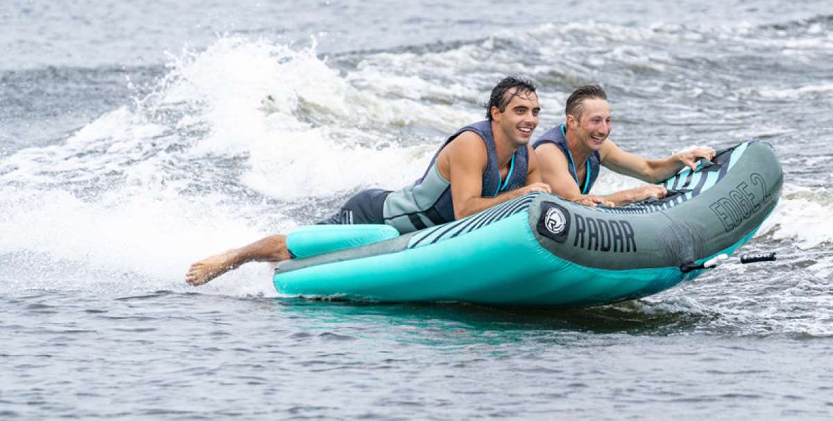 Radar Edge 2 Inflatable Towable Tube 2022 - Blue tube with black stripes and white logo on front, being pulled by a boat in choppy water.