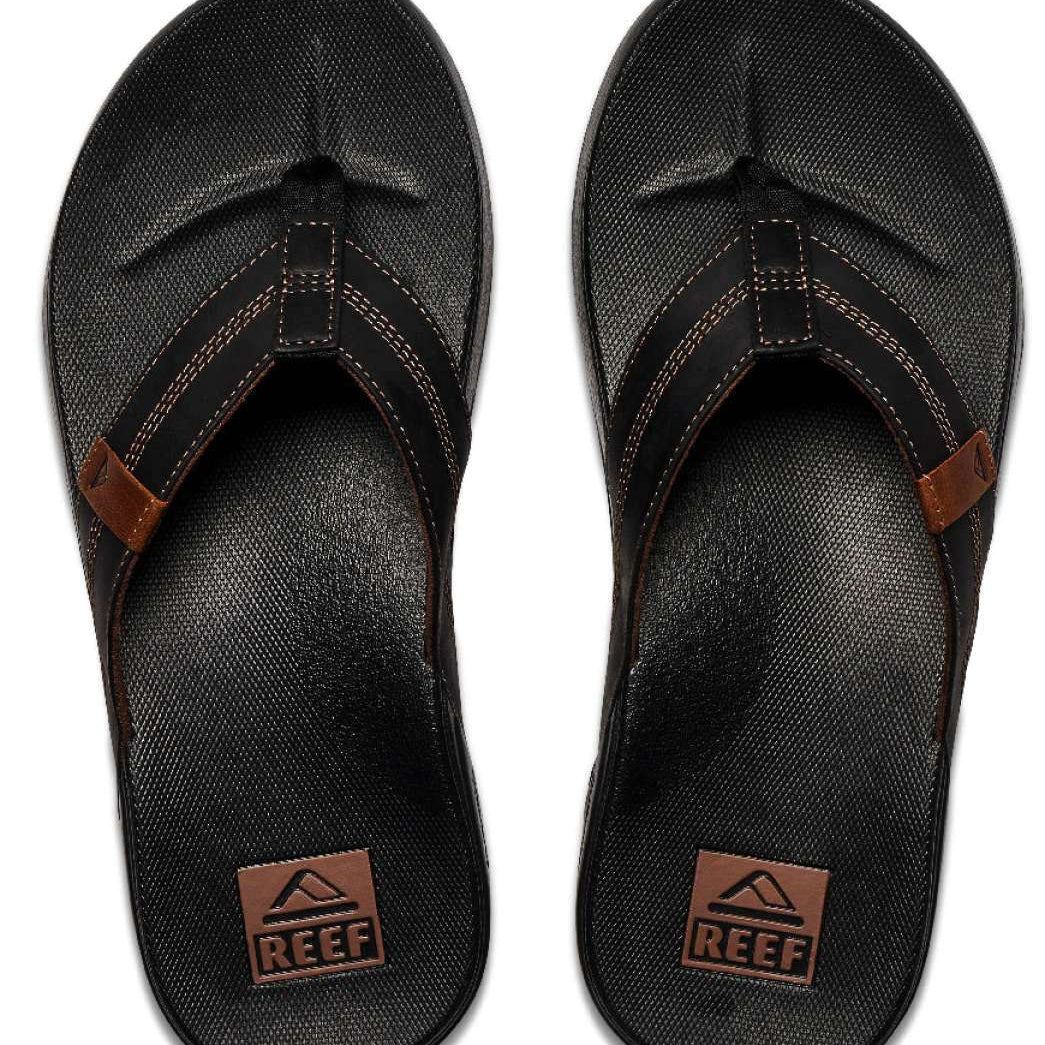 Reef Cushion Phantom LE Sandal 2022 - A pair of black sandals with a strap that goes between the big and second toe, featuring a brown logo on the strap.