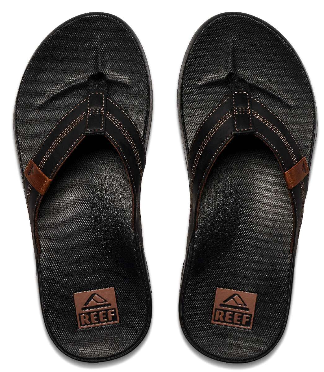 Reef Cushion Phantom LE Sandal 2022 - A pair of black sandals with a strap that goes between the big and second toe, featuring a brown logo on the strap.