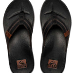 Reef Cushion Phantom LE Sandal 2022 - A pair of black sandals with a strap that goes between the big and second toe, featuring a brown logo on the strap.
