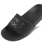 Reef X Life Is Good Women's Slide 2022 - A pair of black slide sandals with a logo on the strap.