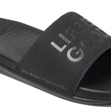 Reef X Life Is Good Women's Slide 2022 - A black slide sandal with a logo on the strap and a textured footbed.