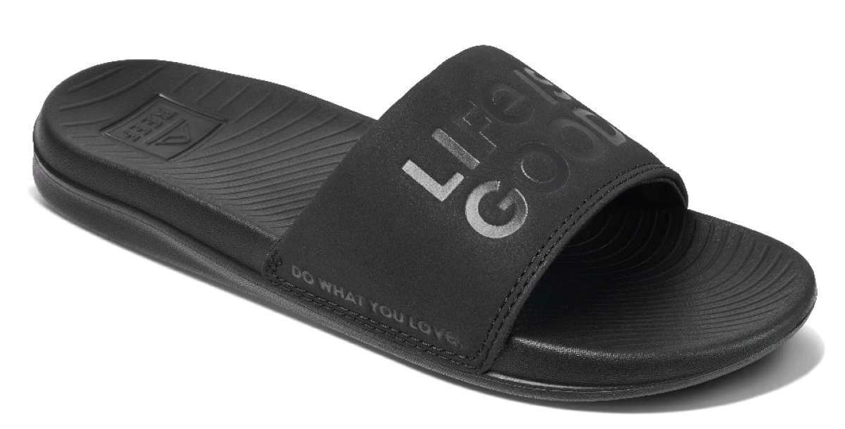 Reef X Life Is Good Women's Slide 2022 - A black slide sandal with a logo on the strap and a textured footbed.