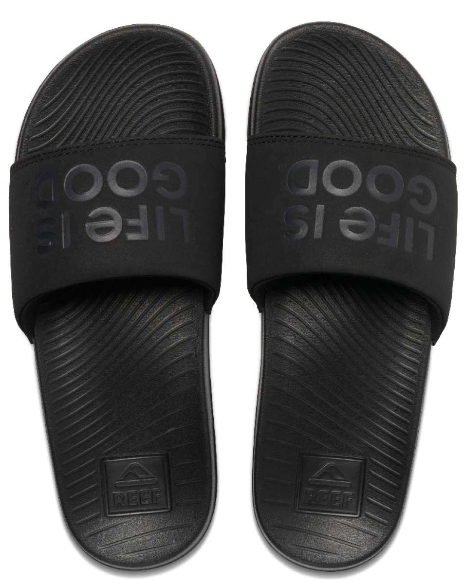 Reef X Life Is Good Women's Slide 2022 - A pair of black slide sandals with a textured footbed and embossed logo on the strap.