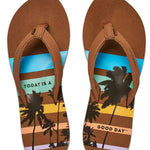 Reef Women's X Life Is Good Sandal - A pair of brown sandals with a palm tree and sunset design on the straps.