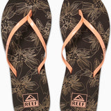 Reef Women's Bliss-Full Sandal - A pair of women's sandals with a floral pattern on a dark brown background, featuring light-colored flowers and leaves.