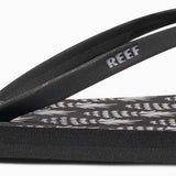 Reef Women's Bliss-Full Sandal 2020 - A pair of black sandals with a pink logo on the strap.