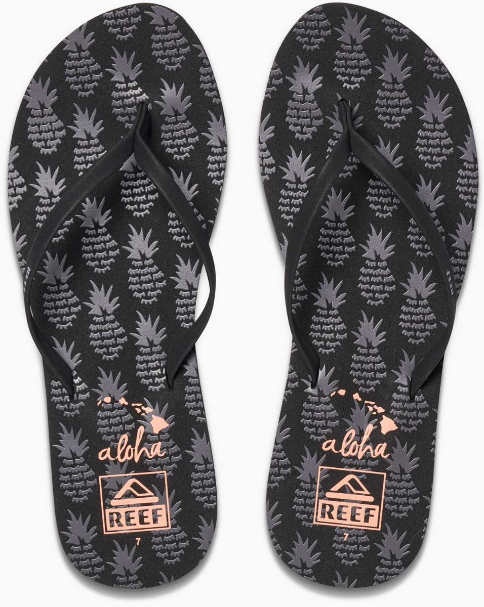 Reef Women's Bliss-Full Sandal 2020 - A pair of black sandals with a strap across the foot and a toe post, featuring a pineapple pattern on the straps.