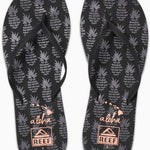 Reef Women's Bliss-Full Sandal 2020 - A pair of black sandals with a strap across the foot and a toe post, featuring a pineapple pattern on the straps.