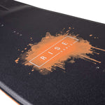 Ronix Ladies Rise Wakeboard 2022 - A black wakeboard with a white logo and lettering on top, featuring a woman riding it in the background.