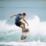 Ronix Party Impact Wake Vest 2022 - A blue, red, and white striped wake vest with black accents on a sandy beach background.