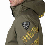 Rossignol All Speed Insulated Jacket 2022-2023 - A dark green jacket with a black logo patch on the left sleeve and yellow lettering on the right sleeve.