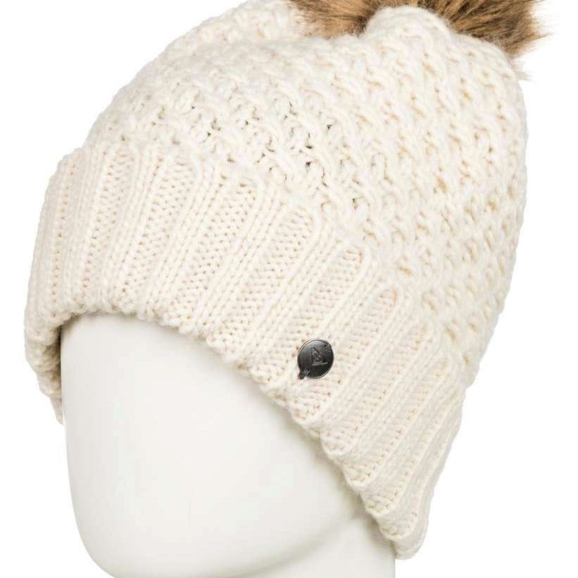 Roxy Women's Blizzard Beanie 2022 - A cream-colored beanie with a cable-knit pattern and a brown faux fur pom-pom on top.