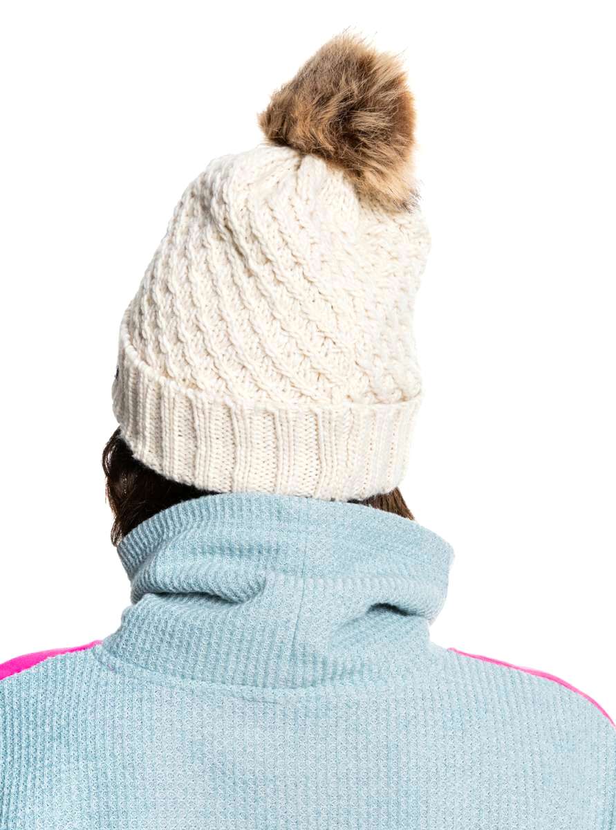 Roxy Women's Blizzard Beanie 2022 - A cream-colored beanie with a cable-knit pattern and a brown faux fur pom-pom on top.