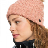 Roxy Women's Blizzard Beanie 2023 - A dusty rose-colored beanie with a ribbed pattern and a faux fur pom-pom on top.