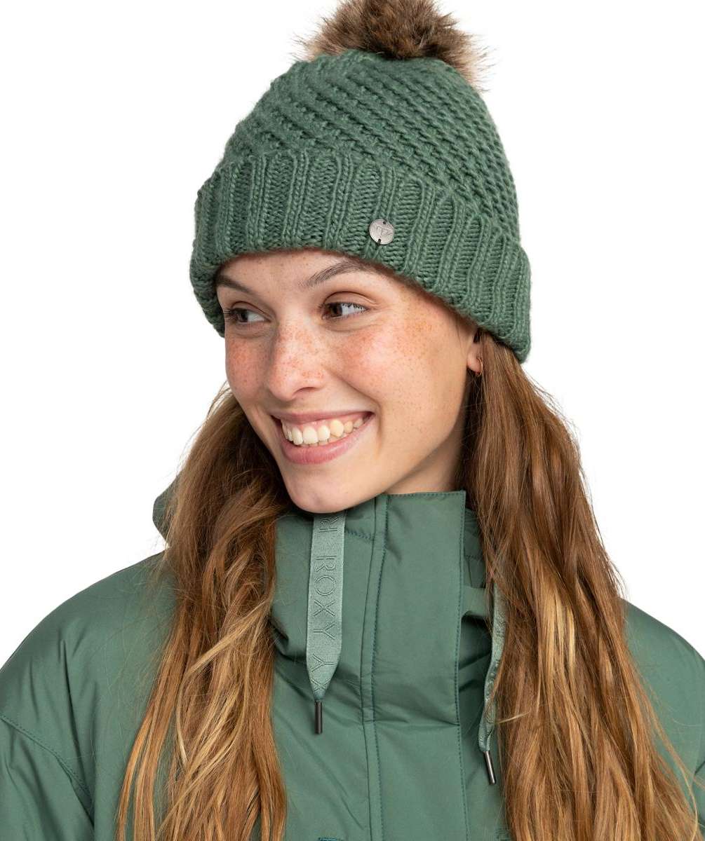 Roxy Women's Blizzard Beanie 2024 - A green beanie with a brown faux fur pom-pom on top.