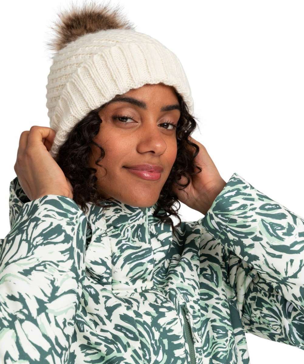 Roxy Women's Blizzard Beanie 2024 - A cream-colored beanie with a ribbed pattern and a brown faux fur pom-pom on top.
