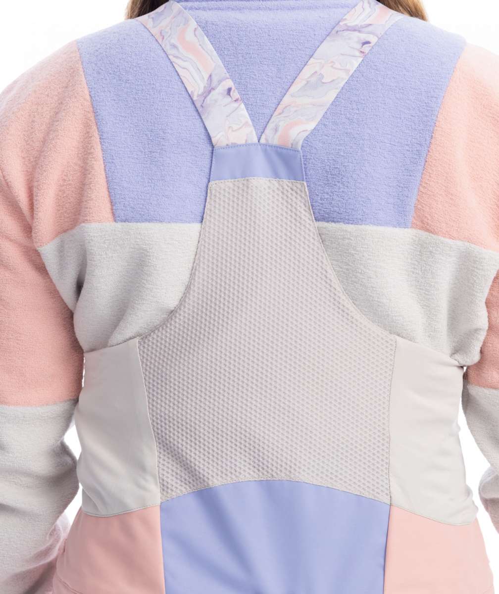 Roxy Women's Chloe Kim Bib Pant 2023 - A pair of snow pants with a subtle floral pattern in shades of pink and purple, featuring a white background.