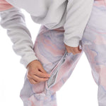 Roxy Women's Chloe Kim Insulated Pant 2023 - A pair of pink and grey snow pants with a marbled pattern, featuring a zipper on the left leg.