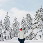 Roxy Women's Dusk Warmlink Insulated Jacket 2024 - A woman in a white jacket with black accents and a hood, standing on a snowy mountain slope.