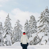 Roxy Women's Dusk Warmlink Insulated Jacket 2024 - A woman in a white jacket with black accents and a hood, standing on a snowy mountain slope.