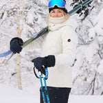 Roxy Women's Dusk Warmland Insulated Jacket - A black jacket with a white logo on the left chest and a hood, worn by a model posing in front of snowy trees.