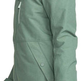 Roxy Women's Presence Insulated Parka Jacket 2024 - A woman with curly brown hair is wearing a light green parka jacket with a hood and a black rectangular patch on the left sleeve that says "ROXY" in white letters.