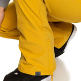 Roxy Women's Rising High Pant 2023 - A pair of yellow snow pants with a zippered pocket on the side and a small black tag near the hem.