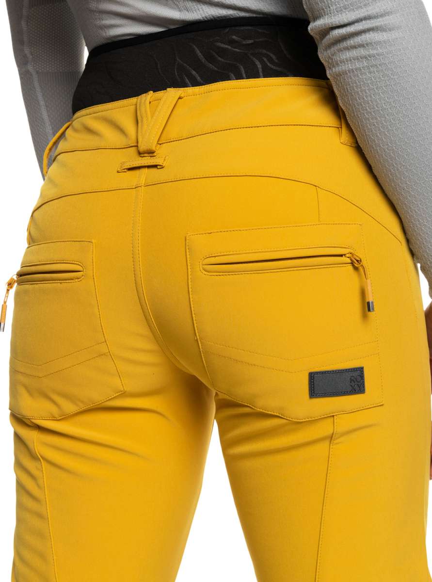 Roxy Women's Rising High Pant 2023 - A pair of yellow ski pants with zippered pockets and a black waistband.