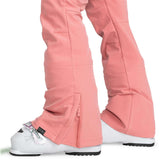 Roxy Women's Rising High Pant 2024 - A pair of pink snow pants with a zippered pocket on the side and a black tag near the bottom hem.