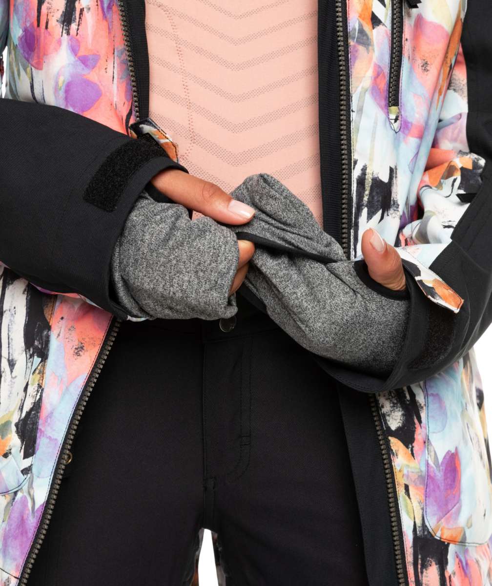 Roxy Women's Stated Insulated Jacket - A woman wearing a black jacket with a pink and purple abstract floral pattern on the back, holding it open to show the interior lining.