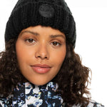Roxy Women's Tram Beanie 2023 - A black beanie with a circular patch on the front that says "ROXY" in white letters.