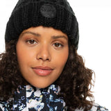 Roxy Women's Tram Beanie 2023 - A black beanie with a circular patch on the front that says "ROXY" in white letters.