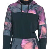 Roxy Women's Winter Valley Hoodie 2024 - A woman with blonde hair wearing a black hoodie with pink and purple floral designs on the chest, sleeves, and hood.