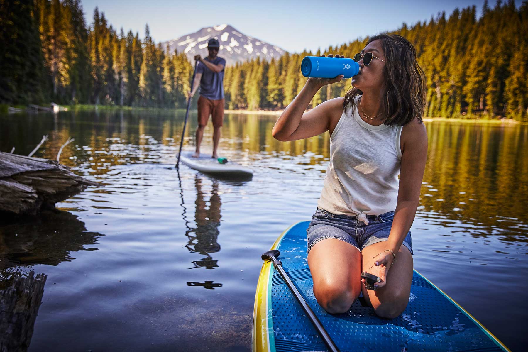 Hydro Flask 24oz Standard Mouth Water Bottle - A blue water bottle with a white logo on the side, held by a person in a kayak.