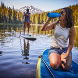 Hydro Flask 24oz Standard Mouth Water Bottle - A blue water bottle with a white logo on the side, held by a person in a kayak.