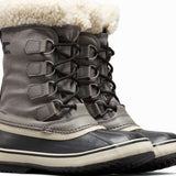 Sorel Ladies Winter Carnival Boot 2022-2023 - A pair of tall, dark brown boots with a thick cream-colored fur trim around the top and laces.