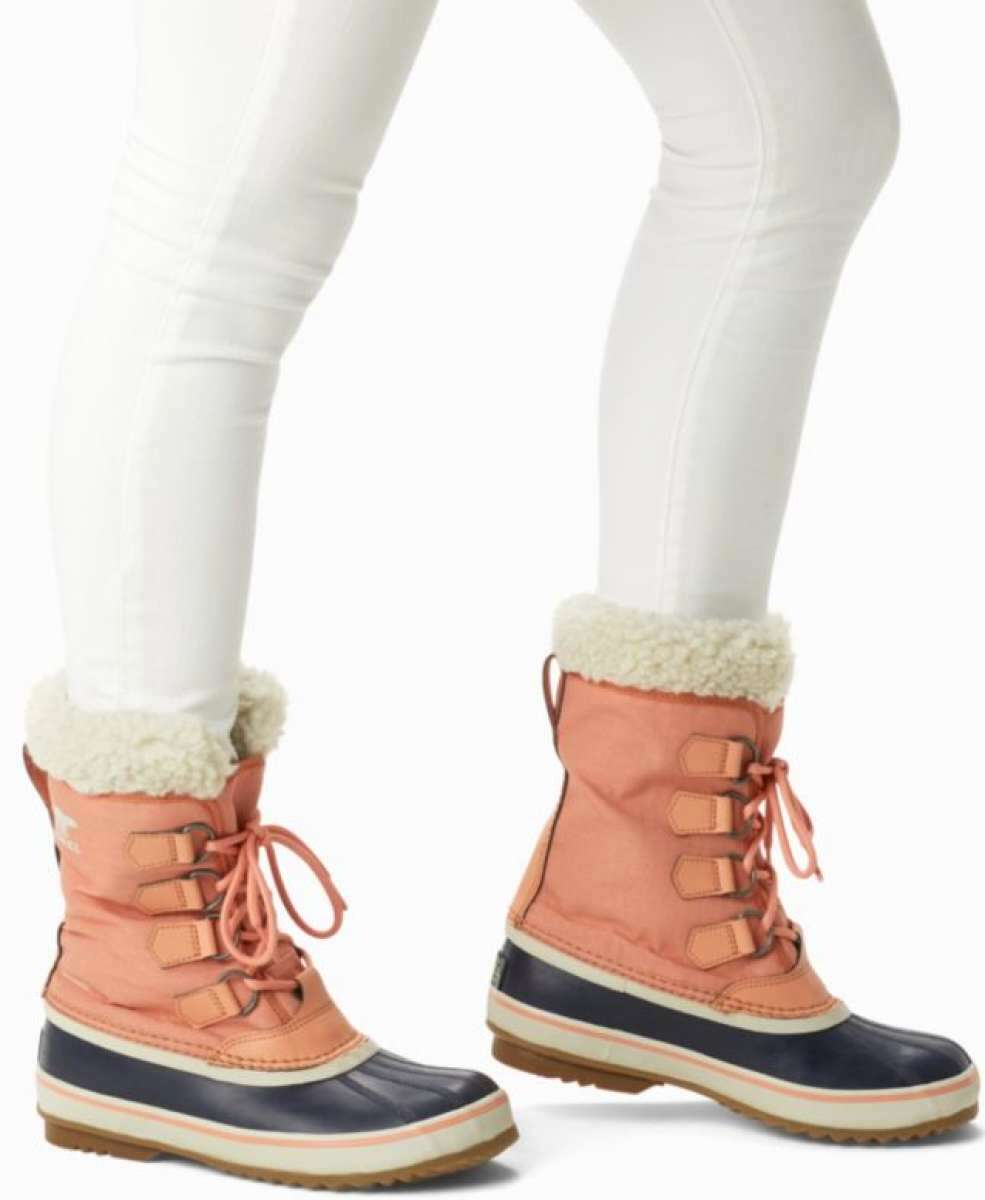 Sorel Ladies Winter Carnival Boot 2022-2023 - A pair of tall, dark brown boots with a thick cream-colored fur lining around the top and a sturdy sole.