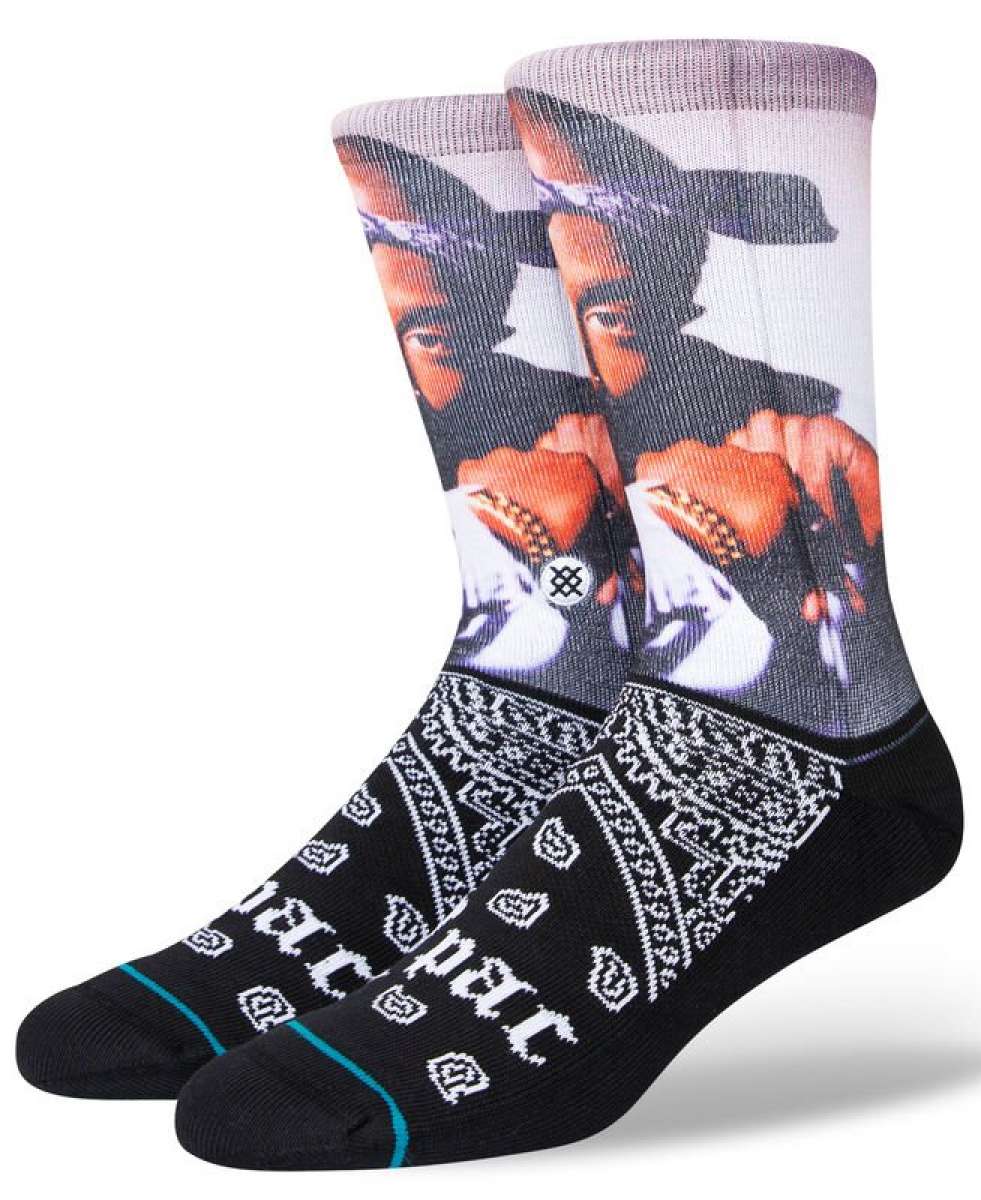 Stance Makaveli Crew Sock 2023 - A pair of crew socks feature a large image of Tupac Shakur's face on the top portion, with his hand raised to his chin and wearing a black bandana wrapped around his head.
