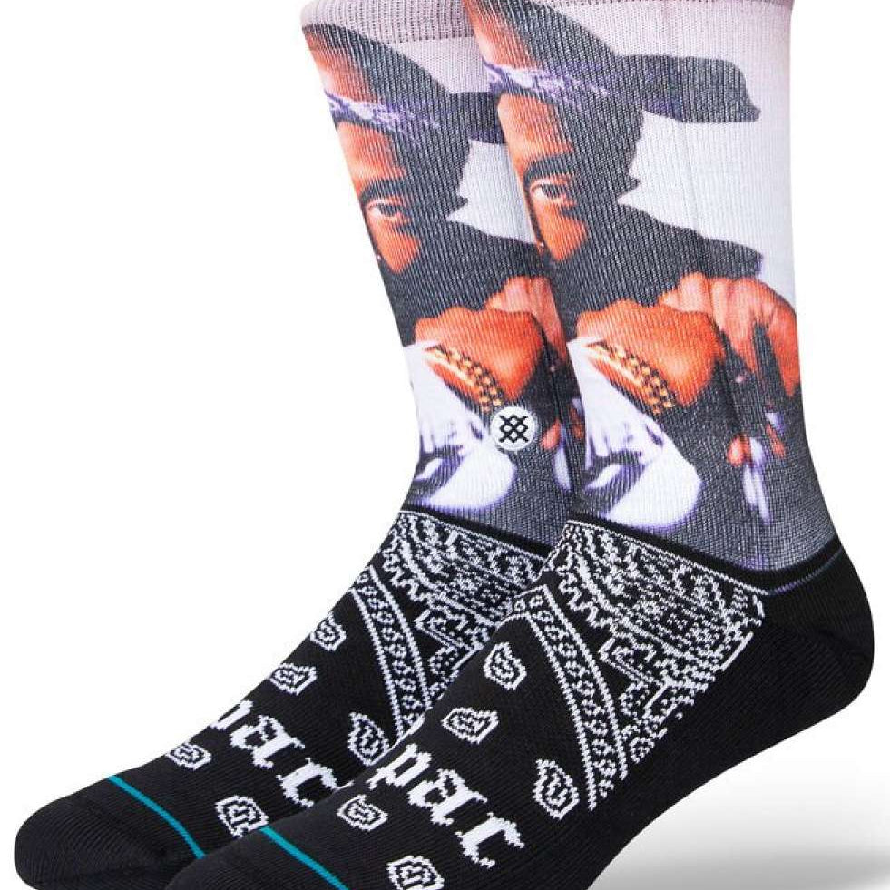 Stance Makaveli Crew Sock 2023 - A pair of crew socks feature a large image of Tupac Shakur's face on the top portion, with his hand raised to his chin and wearing a black bandana wrapped around his head.